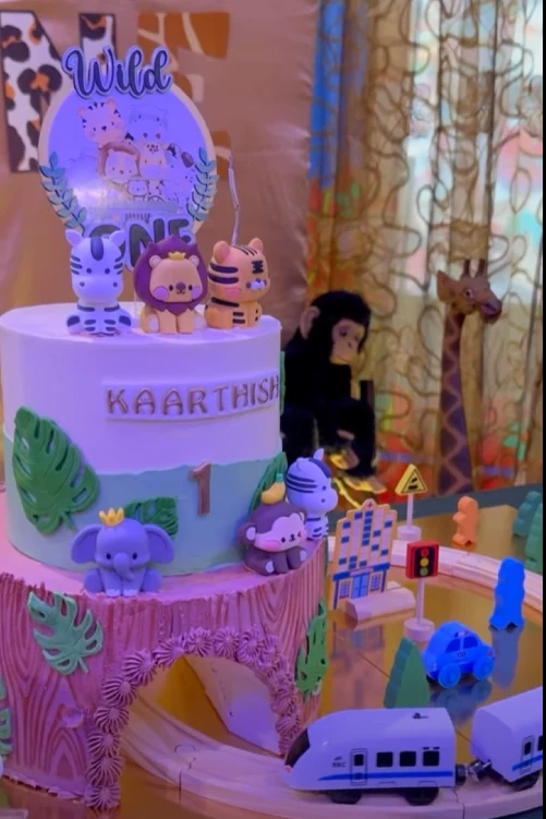 Pastel wild one birthday cake with animal figures and train decorations